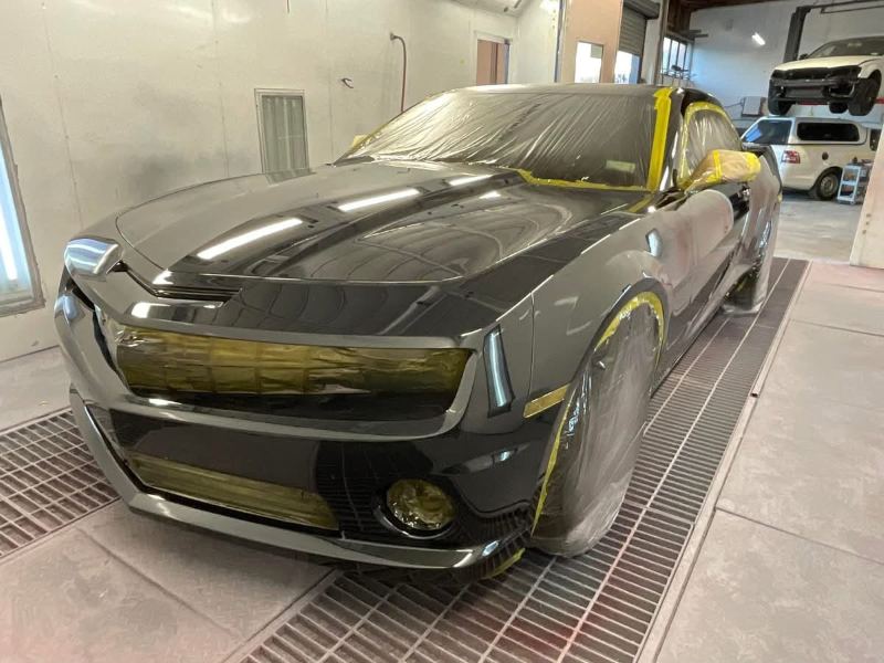 Black Camaro masked up in the spray booth with its front end freshly painted