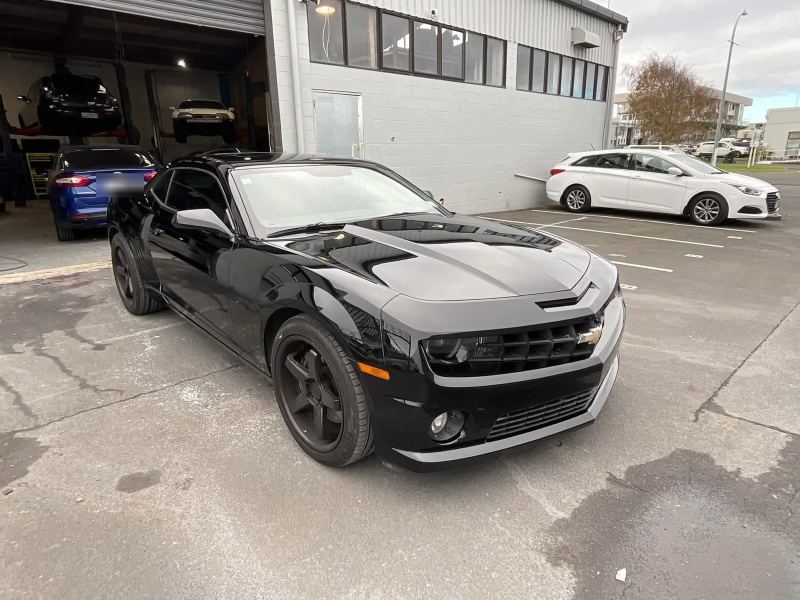 Finished black Camaro parked outside the workshop